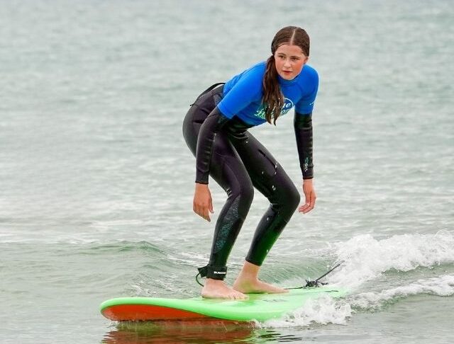 Surfer riding a small wave during a Blue Horizons surf lesson on the Pembrokeshire coast.