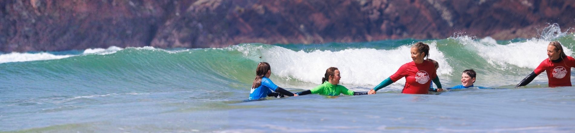 Adaptive surf instructors supporting children during an inclusive surfing lesson with Blue Horizons on the Pembrokeshire coast.