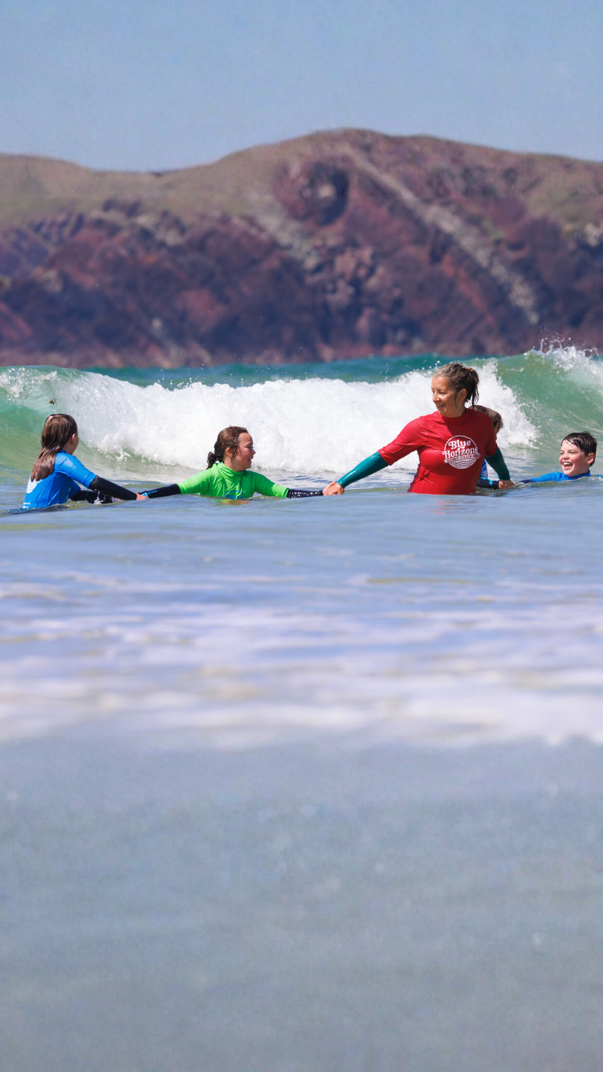 Adaptive surf instructors supporting children during an inclusive surfing lesson with Blue Horizons on the Pembrokeshire coast.
