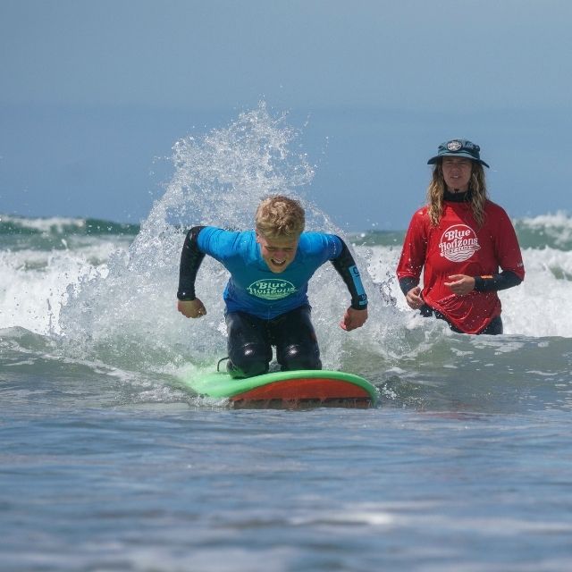 Young surfer riding a wave during an adaptive surf lesson with a Blue Horizons instructor in Pembrokeshire.
